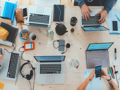 overhead view of people at a table working on laptops