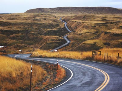 winding road going through hills toward a mountain