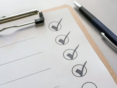 clipboard with checklist with four checked circles and a black and silver pen to the right-hand side of the image