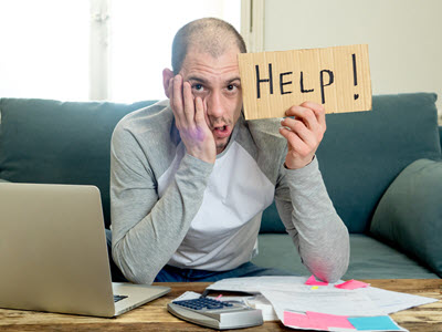 Person at a laptop holding up a sign that says help