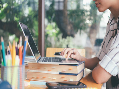 person using laptop stacked on top of two books