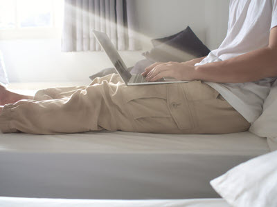 person sitting on a bed using a laptop