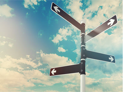 a street sign pointing in different directions against a blue, cloudy sky