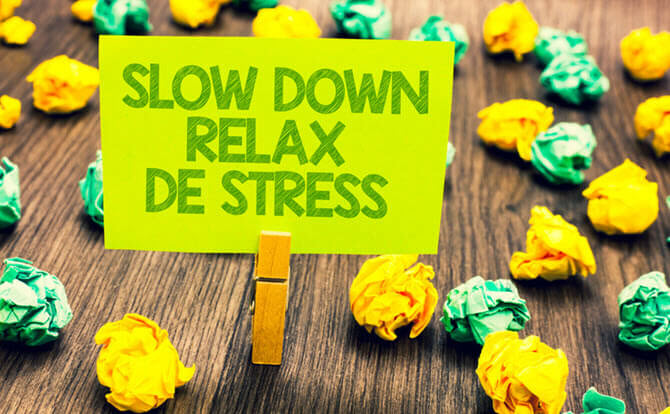 Sign that reads: slow down, relax, destress amidst many pieces of balled up yellow and green paper