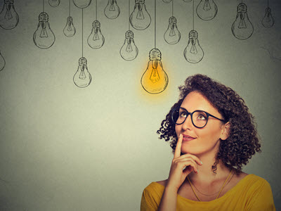 a person looking up toward light bulbs, one of which is glowing yellow