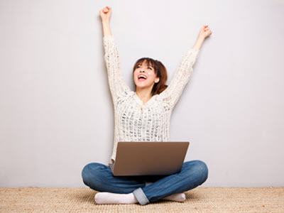 a person sitting on the floor using a laptop with arms stretched up