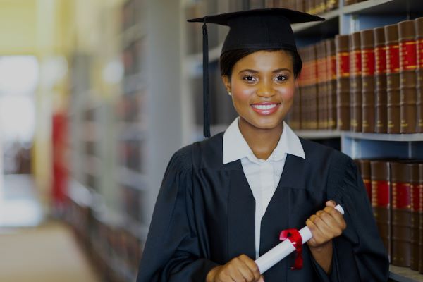 female graduate with diploma standing in front of bookcase