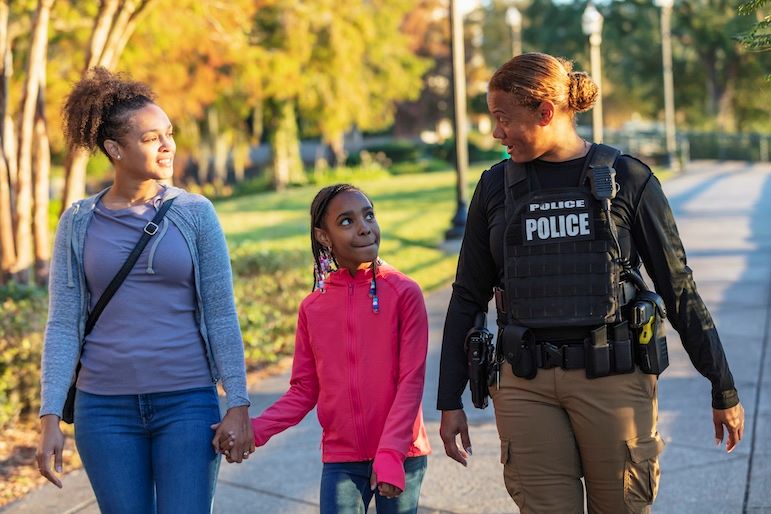 community oriented police officer walking with mother and child