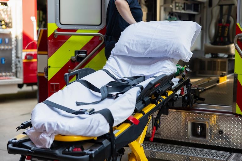emergency services stretcher being put into ambulance