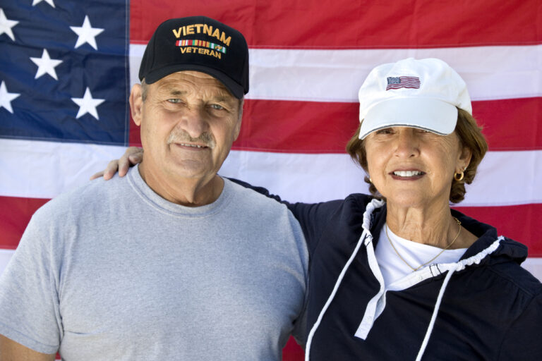 veteran and partner in front of American flag