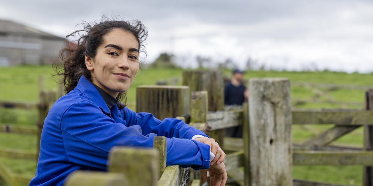 female environmental scientist leaning on fence post